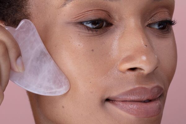 close up of woman massaging face with rose quartz royalty free image 1728668234 Dermatologists Say This Affordable Tool Can Reduce Puffiness—Here's Exactly How To Use It