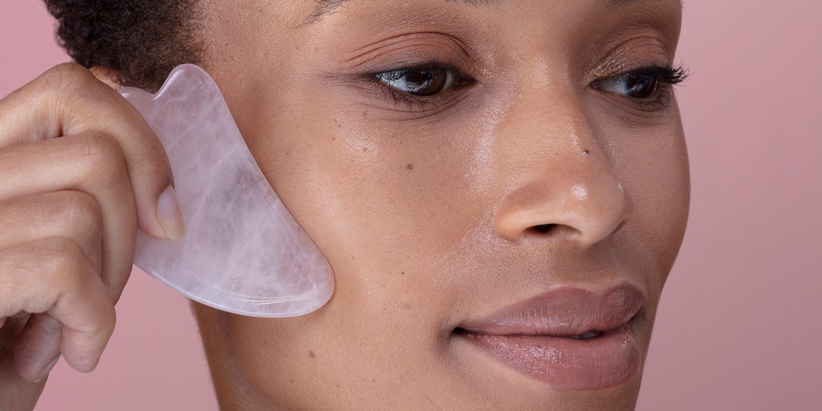 close up of woman massaging face with rose quartz royalty free image 1728668234 Dermatologists Say This Affordable Tool Can Reduce Puffiness—Here's Exactly How To Use It